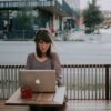 woman in gray shirt sitting on bench in front of MacBook